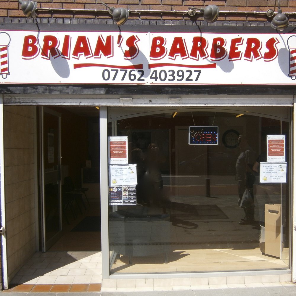 The real front of Brian’s Barbers on Main Street, with its red and white sign and glass entrance